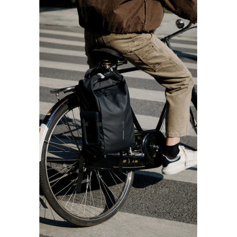 Sac à dos imperméable fixé à un porte-bagages de vélo, en situation réelle de déplacement urbain