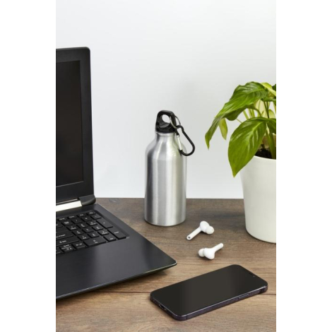 Bouteille publicitaire en aluminium posée sur un bureau avec ordinateur et écouteurs, ambiance professionnelle