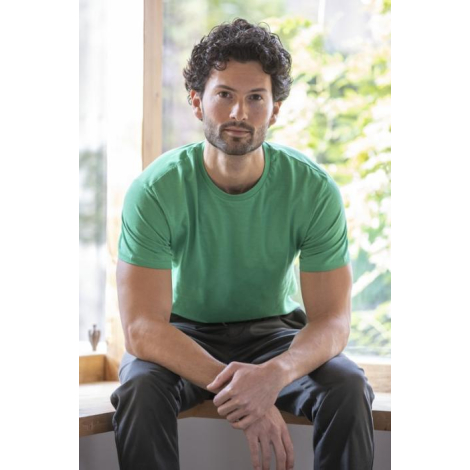 T-shirt Heros vert porté par un homme assis en intérieur, coupe classique