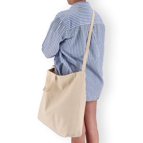 Sac porté en bandoulière par une personne en chemise rayée, sans marquage visible