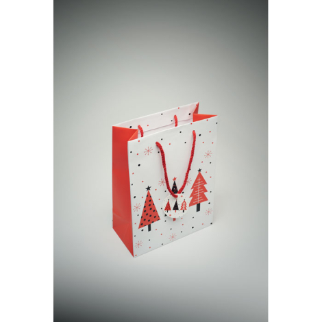 Vue plongeante d’un sac cadeau décoré avec cordons rouges et étiquette assortie