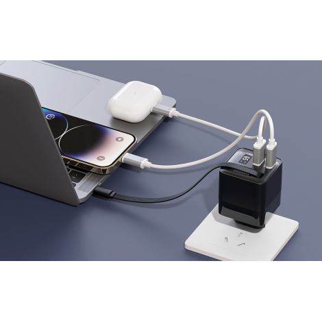 Chargeur GaN 65W branché au mur, reliant un laptop, un smartphone et des écouteurs.