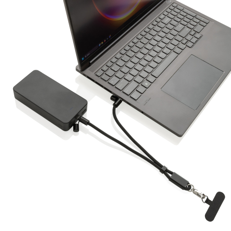 Bracelet téléphone noir avec câble intégré branché à un ordinateur et une batterie externe.