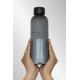 Bouteille grise translucide tenue à deux mains avec surface nervurée
