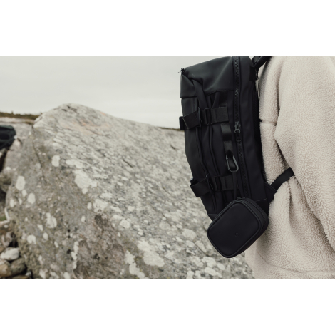 Trousse de secours noire attachée à un sac à dos en extérieur, sans personnalisation.