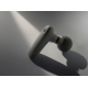 Pistolet de massage noir incliné sur surface grise avec ombres, sans personnalisation.