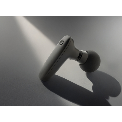Pistolet de massage noir incliné sur surface grise avec ombres, sans personnalisation.
