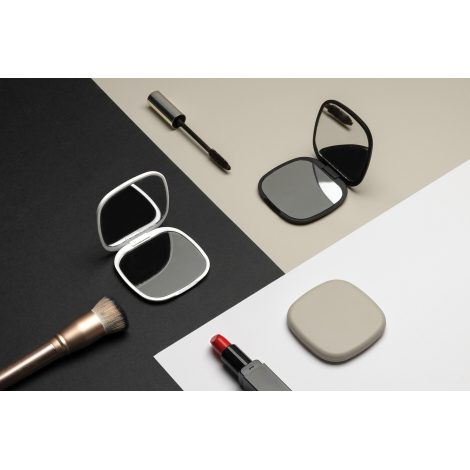 Deux miroirs ouverts noir et blanc posés avec accessoires de maquillage, sans personnalisation.