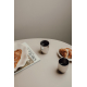 Deux tasses en métal sur une table, l’une remplie de boisson, avec croissant et magazine.