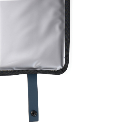 Détail d’un coin du coussin gris clair avec patte bleue et bouton pression, sans marquage visible.
