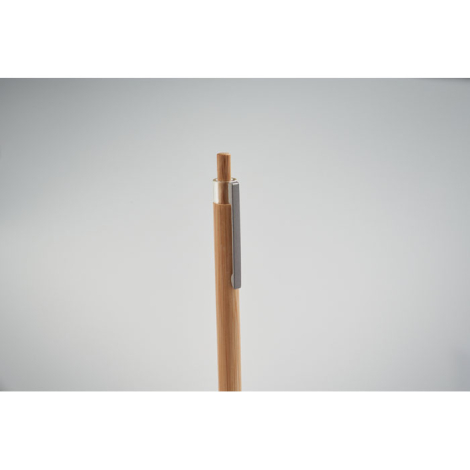 Gros plan sur la partie supérieure d’un stylo en bambou avec bouton poussoir et clip métallique gris, sans marquage.