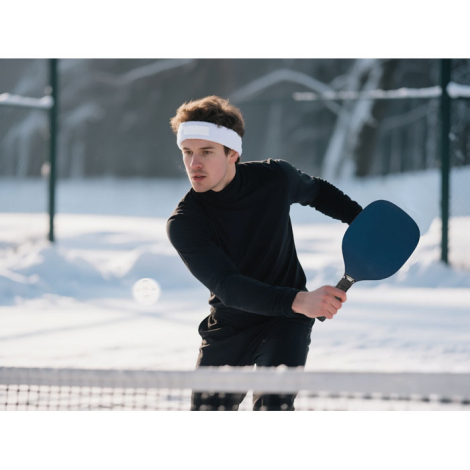 Bandeau blanc porté par un joueur de tennis en extérieur, sans marquage.