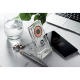 Chargeur sans fil transparent sur un bureau avec smartphone, marquage visible sur le socle avant.