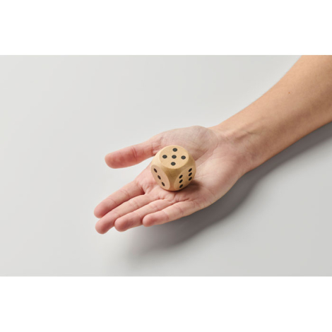 Dé en bois Schima 3 cm tenu dans une main vu de dessus, sans marquage.