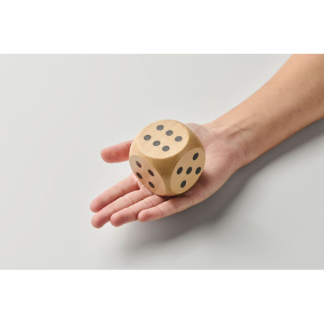 Dé en bois Schima 5 cm tenu dans une main vu de dessus, sans marquage.