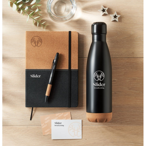 Bouteille noire avec base en liège, carnet assorti et stylo posés sur une table avec carte de visite, marquage visible.