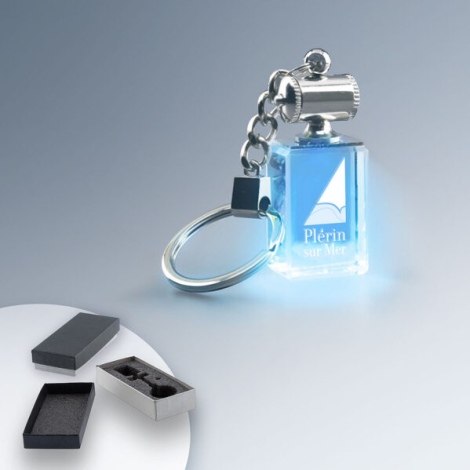 Porte-clés rectangulaire en verre transparent éclairé par une lumière bleue intégrée, marquage visible sur la face avant.