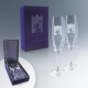 Coffret rigide avec deux flûtes à champagne en verre, intérieur satiné, marquage visible sur chaque flûte.