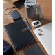 Carnet A5 noir en PU souple posé sur une table en bois avec accessoires de bureau, sans personnalisation.