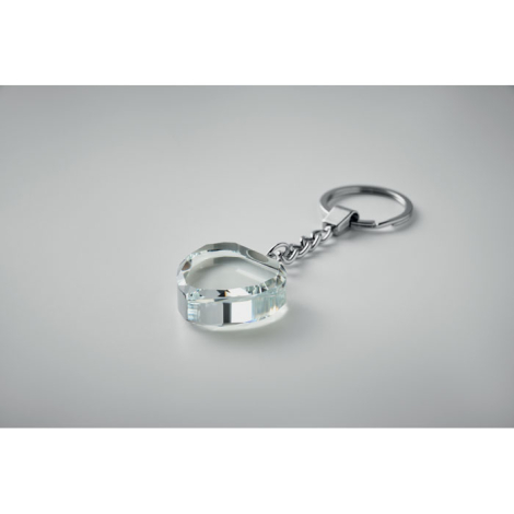 Porte-clés en forme de cœur en verre transparent vu en perspective sur fond gris, sans personnalisation visible.