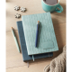 Carnets A5 effet patine bleu clair et bleu foncé posés sur une table avec stylos assortis, sans personnalisation visible.