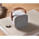 Enceinte blanche posée sur un livre, boutons visibles sur le dessus, sans personnalisation.