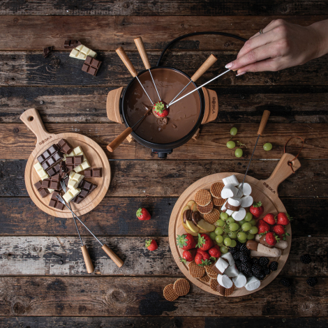 Vue de dessus d’un set à fondue électrique utilisé pour fondue au chocolat, entouré de fruits et biscuits, sans personnalisation Vue de dessus d’un set à fondue électrique utilisé pour fondue au chocolat, entouré de fruits et biscuits, sans personnalisation