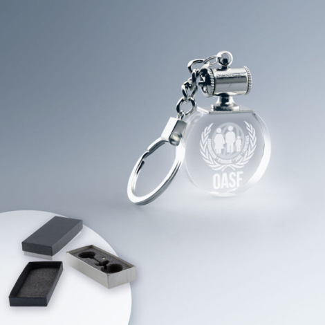 Porte-clés rond en verre transparent avec anneau métallique, vu en perspective, éclairage blanc intégré, marquage centré visible Porte-clés rond en verre transparent avec anneau métallique, vu en perspective, éclairage blanc intégré, marquage centré visible