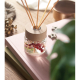 Diffuseur en verre transparent avec bouchon bois clair et tiges de diffusion, posé sur un livre rose dans un décor intérieur.