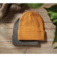 Deux bonnets tricotés superposés sur une surface en bois, l’un jaune moutarde et l’autre gris, sans personnalisation visible.