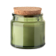 Bougie verte en cire végétale dans un pot en verre teinté avec couvercle en liège posé dessus.