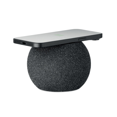 Enceinte sans fil ronde noire avec un smartphone posé sur le dessus en charge sans fil.