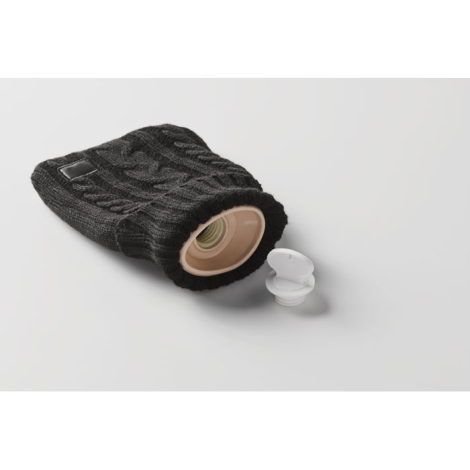 Bouillotte noire avec housse en tricot torsadé couchée, goulot ouvert et bouchon à vis détaché, marquage visible sur l’écusson.