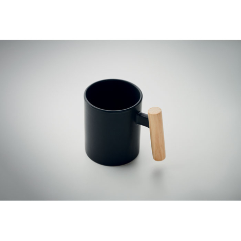 Mug en céramique noir avec anse en bois clair, photographié en plongée.
