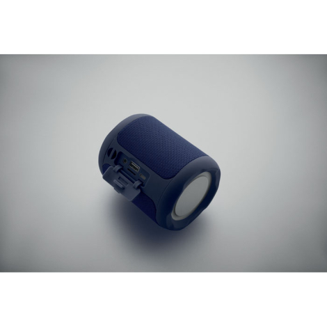 Enceinte cylindrique bleue en ABS vue de dos avec connectiques protégées par un cache souple et extrémités circulaires blanches.