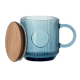 Mug en verre strié bleu avec couvercle en bois posé à côté.