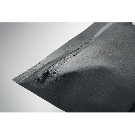 Pochette noire présentée en gros plan avec fermeture zippée recouverte de gouttes d’eau.