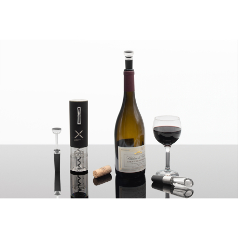 Bouteille de vin et verre rempli posés avec accessoires, marquage visible sur l’emballage cylindrique noir.