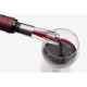 Gros plan d’un bec verseur transparent inséré dans une bouteille servant du vin rouge, sans marquage visible.