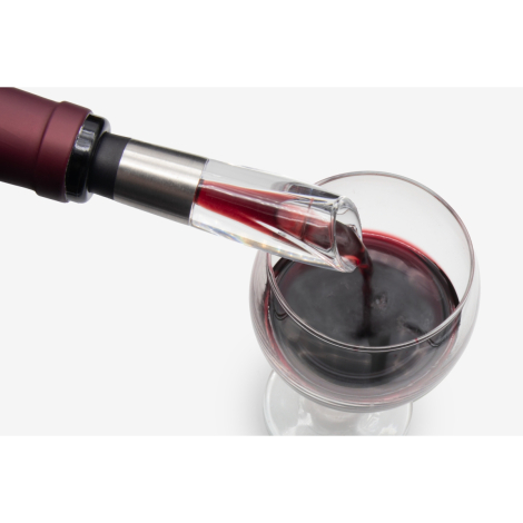 Gros plan d’un bec verseur transparent inséré dans une bouteille servant du vin rouge, sans marquage visible.