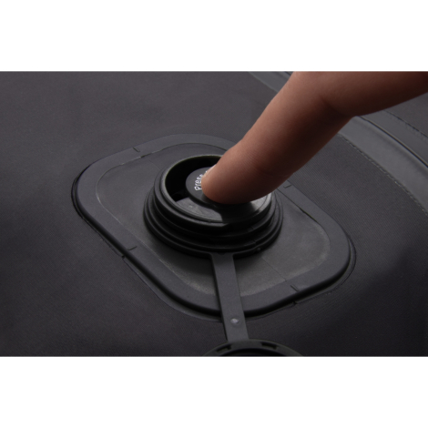 Gros plan d’une valve circulaire noire intégrée dans un sac, doigt appuyant sur le mécanisme, sans marquage visible.