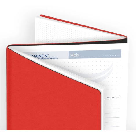 Gros plan d’un agenda rouge entrouvert laissant voir la première page intérieure avec zone de saisie mois et semaine.