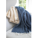 Couvertures recyclées beige et bleue disposées sur un canapé près d’une fenêtre.
