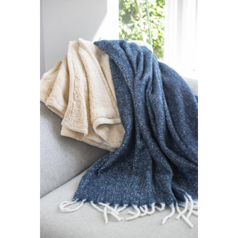 Couvertures recyclées beige et bleue disposées sur un canapé près d’une fenêtre.