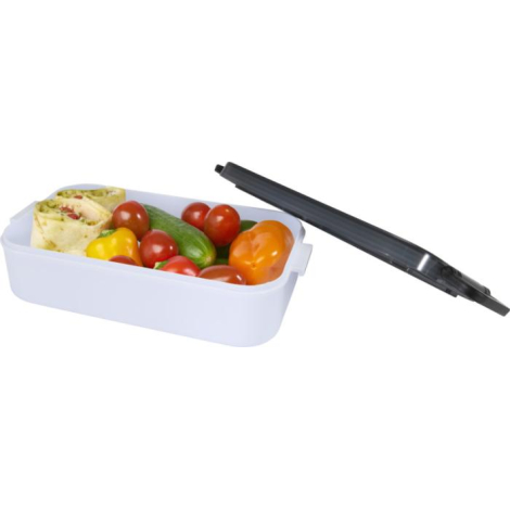Lunch box blanche ouverte contenant des aliments frais, couvercle gris fumé posé à côté.