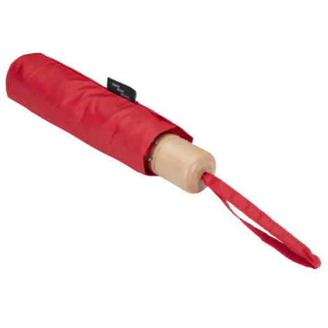 Parapluie rouge replié dans sa housse assortie, poignée claire apparente, posé à plat.