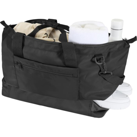 Sac de voyage noir ouvert contenant des accessoires (serviette, bouteille, chaussures), sans marquage visible.