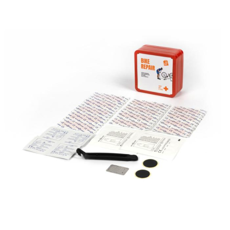 Kit de réparation en métal rouge, ouvert, avec outils et pansements disposés à l’avant et boîte visible à l’arrière. Aucune pers