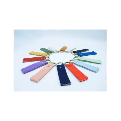 Série de porte-clés multicolores disposés en cercle sur fond clair, anneaux dorés au centre.