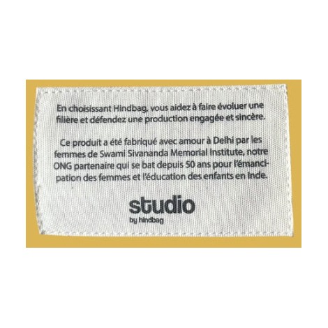 Étiquette blanche cousue sur fond jaune, texte noir visible.